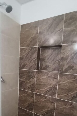 A shower area with dark marble tiles and a visible showerhead.