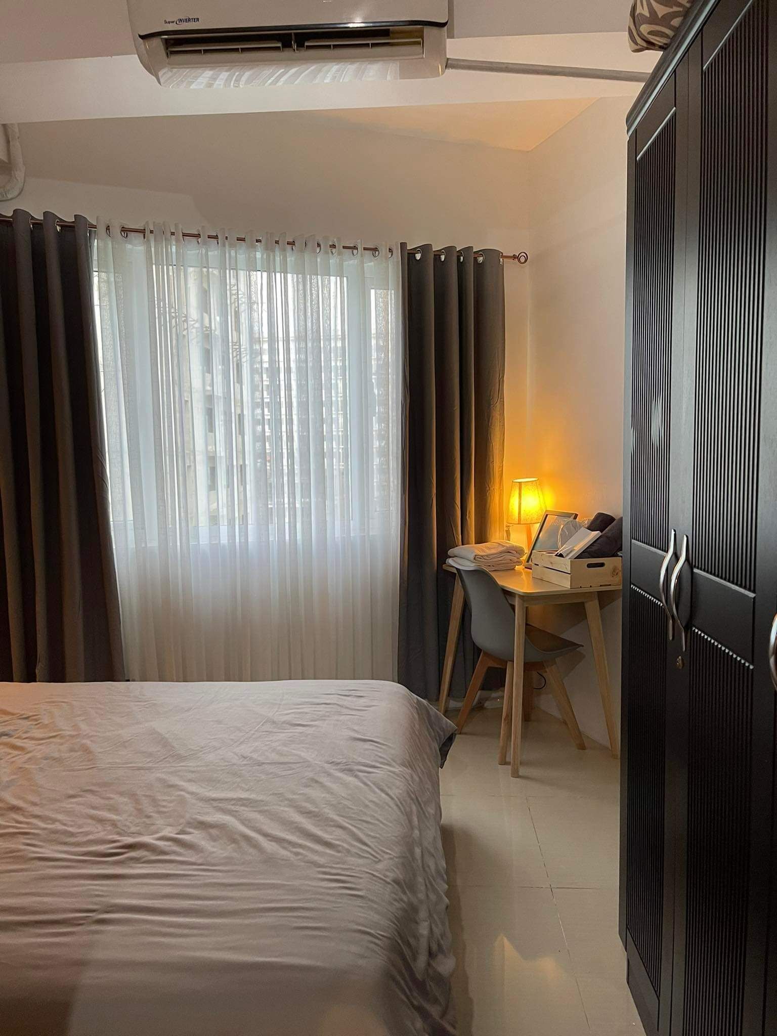Una habitación de hotel con una cama, un escritorio con lámpara y un armario.