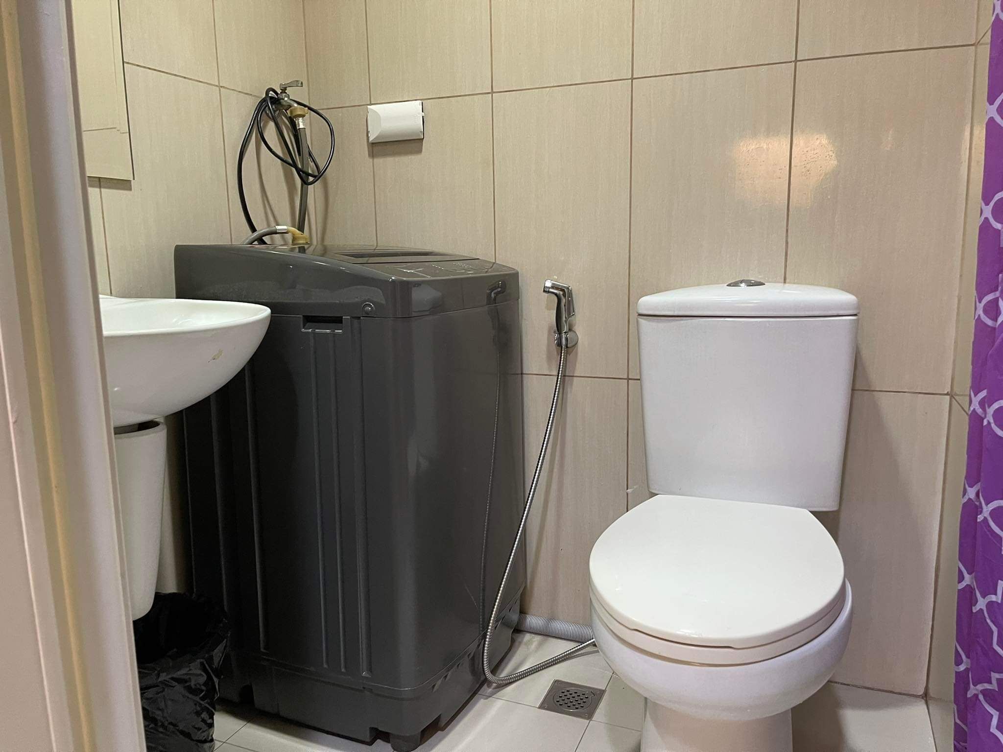 Un baño pequeño con inodoro, lavamanos y lavadora compacta.