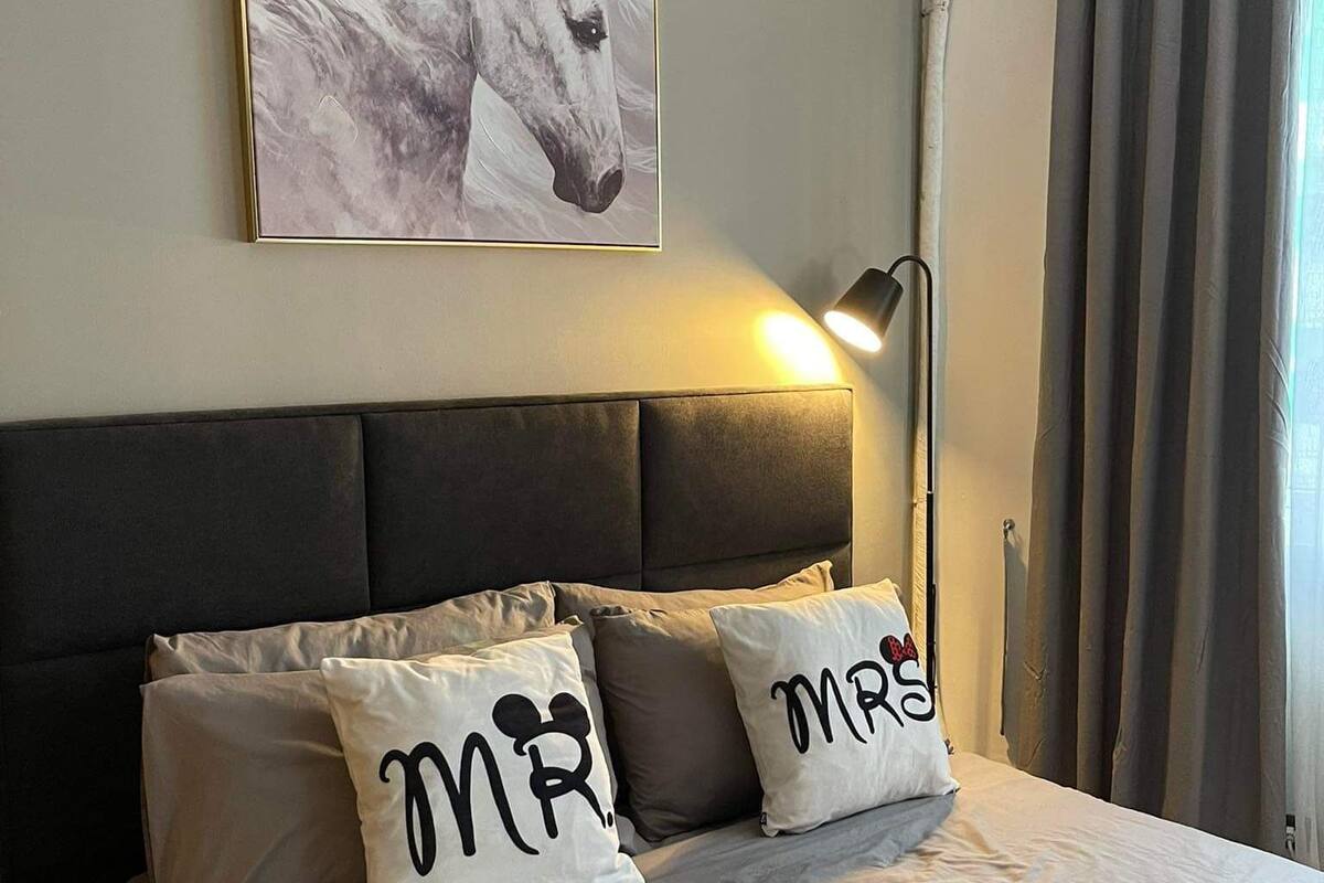 A bedroom with a bed, a headboard, a painting of a horse, and a lamp.