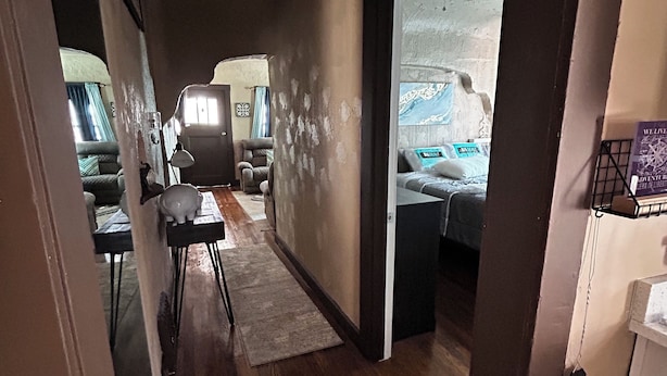 A narrow hallway with wooden flooring leading to a living area with a couch and a coffee table.