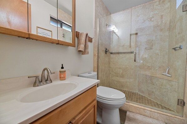 A bathroom with a sink, toilet, and glass-enclosed shower.