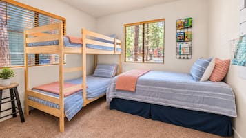 Een slaapkamer met stapelbed, bureau en raam.