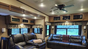 Ein gemütliches Wohnmobil-Interieur mit Ledersofas, einem Esstisch und fest eingebauten Schränken.