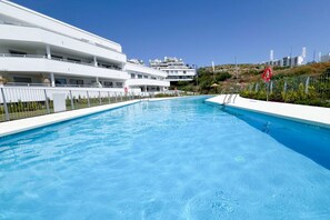 A swimming pool with a white building in the background. - Family penthouse with sea views in Cancelada (Cancelada)