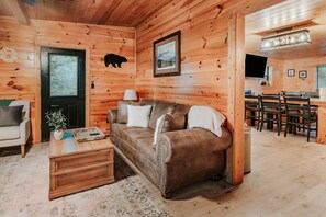 L’intérieur d’un chalet confortable, avec un canapé, une table basse et un coin repas.