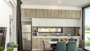 A modern kitchen with a dining area, featuring a built-in microwave, stove, and sink.