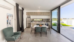 A modern kitchen with a dining area, large windows, and a view of the outdoors.