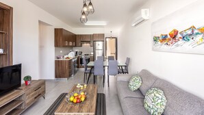 A modern living room with a sofa, coffee table, TV, and artwork. - 2 bedroom apartment in Kapparis AK14 (Kapparis)