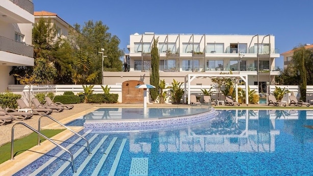A modern hotel with a swimming pool, sun loungers, and a clear blue sky. - 2 bedroom apartment in Kapparis AK14 (Kapparis)