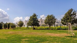 A grassy field with trees and modern buildings in the background. - 2 bedroom apartment in Kapparis AK14 (Kapparis)