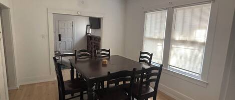 Un espace repas comprenant une table et des chaises en bois, un tapis et un luminaire au plafond.