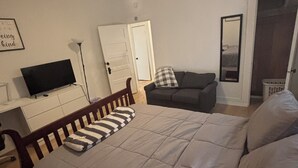Ein Schlafzimmer mit Bett, Fernseher, Deckenventilator, Kommode und Tür.