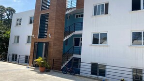 A multi-story residential building with a central staircase, a balcony, and a potted plant.