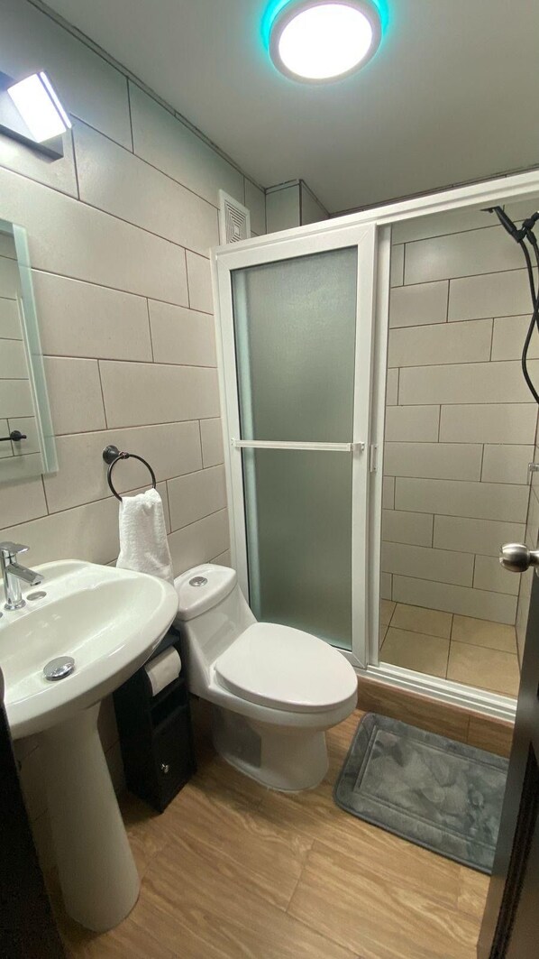 Un baño moderno con lavamanos, inodoro y cabina de ducha de vidrio.