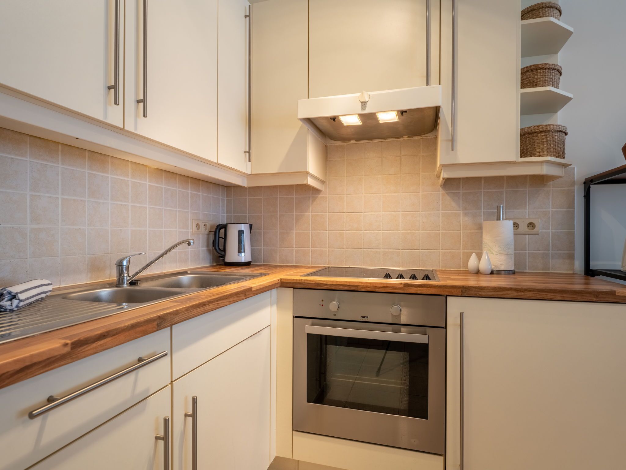 A modern kitchen with a stainless steel oven, a built-in sink, and wooden countertops.