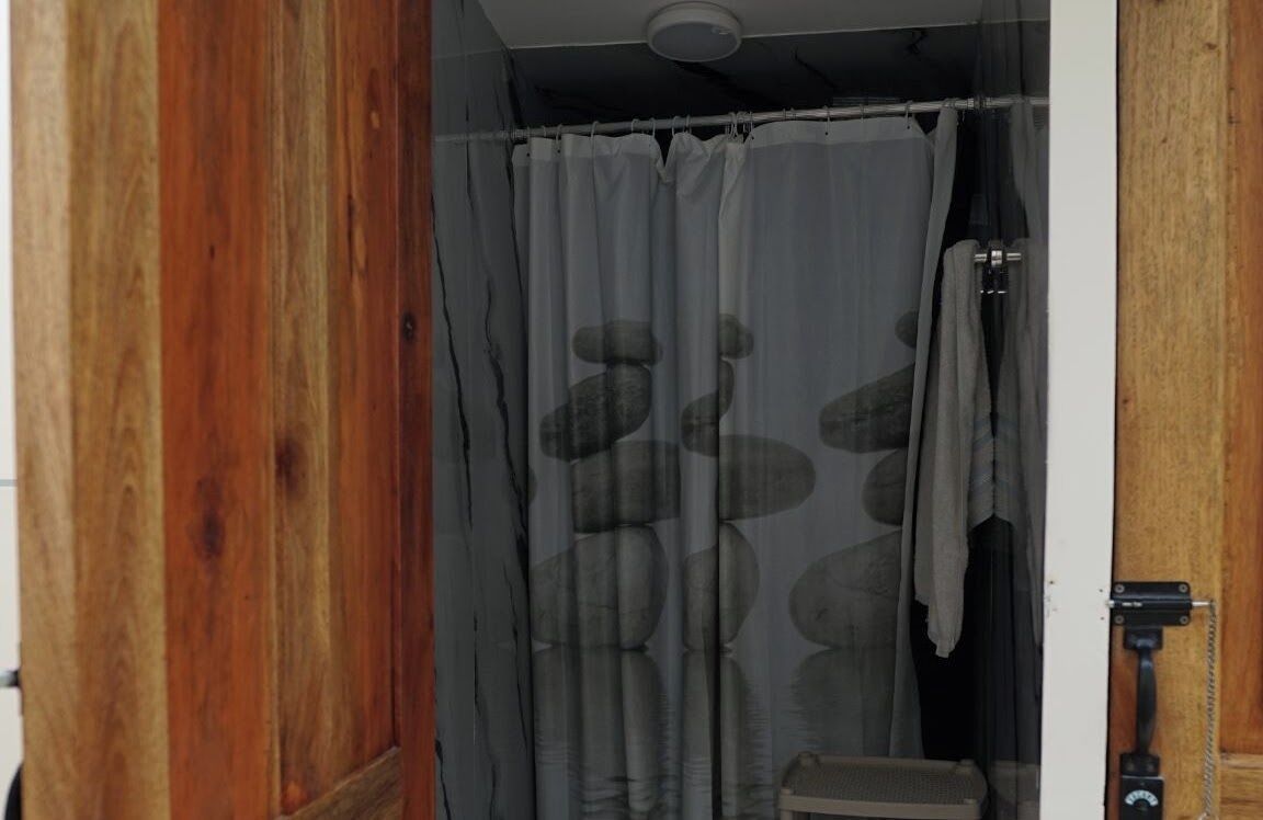 Puerta de madera que da a un baño con cortina de ducha estampada con un diseño de piedra.