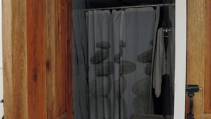 Eine Holztür führt zu einem Badezimmer mit einer Duschvorhangs, der ein Steinmuster zeigt.
