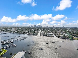 A marina with multiple boats docked, a city skyline in the background, and a clear sky. - Gorgeous Private Beachfront 2br (Fort Lauderdale)