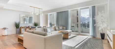 A modern living room with a sofa, coffee table, and a dining area with a table and chairs.