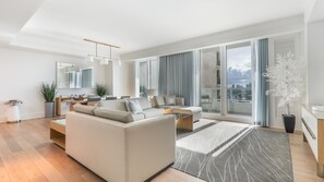 A modern living room with a sofa, coffee table, and a dining area with a table and chairs. - Gorgeous Private Beachfront 2br (Fort Lauderdale)