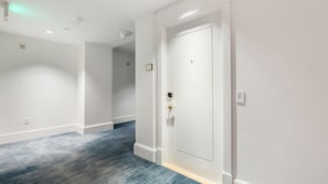 A hallway with a white door, a light switch, and a smoke detector on the wall. - Gorgeous Private Beachfront 2br (Fort Lauderdale)