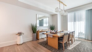 A modern dining area with a wooden table, chairs, a small side table, and a potted plant. - Gorgeous Private Beachfront 2br (Fort Lauderdale)