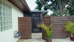Une maison avec un patio carrelé, une porte en bois et des plantes en pot.