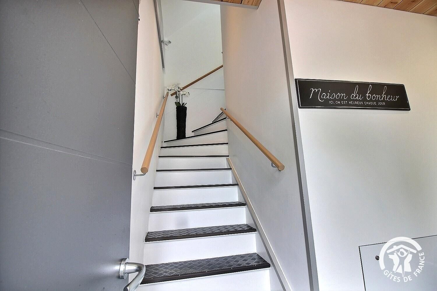 A staircase with a wooden handrail and a sign that reads "Maison du Bonheur".