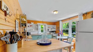 A modern kitchen with wooden walls, a central island, and a view of the outdoors. - Point Prim Cottage: Beach Access and Family Fun (Belfast)