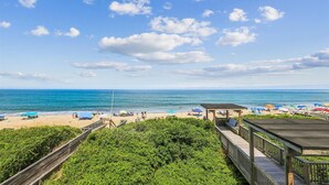 A beach with a wooden boardwalk leading to a gazebo, overlooking the ocean. - Beachfront Duck retreat with 4 king bedrooms, 3 baths, and private beach walkway. (Duck)