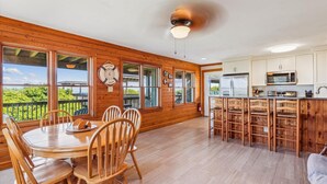 A wooden interior with a dining area, kitchen, and large windows offering a view. - Beachfront Duck retreat with 4 king bedrooms, 3 baths, and private beach walkway. (Duck)