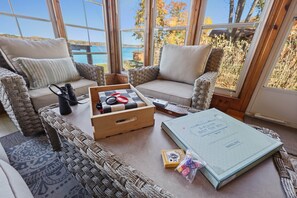 A cozy seating area with wicker furniture, a wooden coffee table, and a view of the outdoors. - The Cozy Cub (Crosslake)