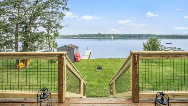 A deck with a view of a lake, a small shed, and a red kayak. - The Cozy Cub (Crosslake)