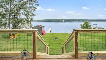 Une terrasse avec vue sur un lac, un petit abri de jardin et un kayak rouge.
