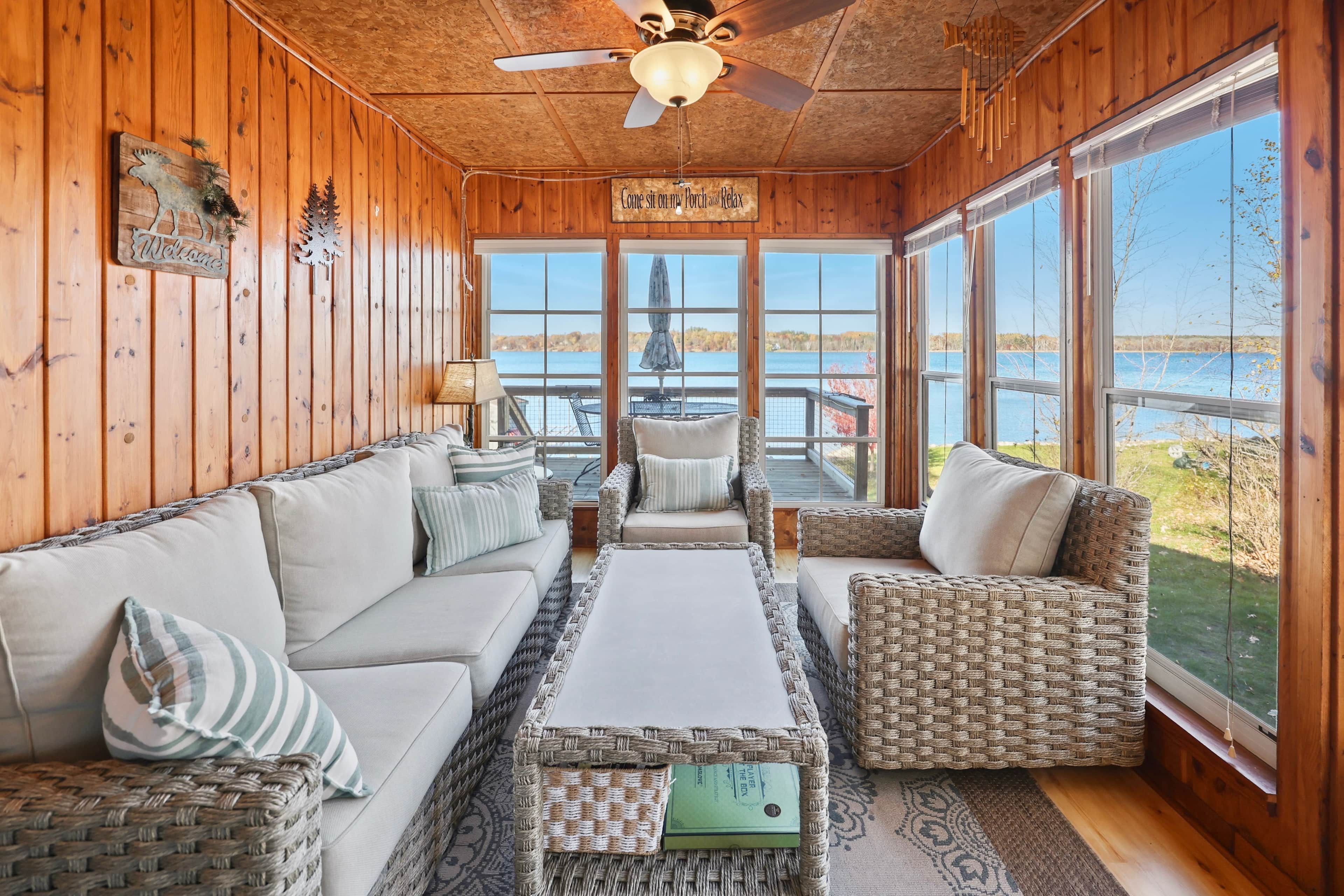 A wooden interior with a sofa, chairs, a table, and a view of the outdoors.