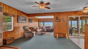A wooden interior with a ceiling fan, a sofa set, and a view through a glass door. - The Cozy Cub (Crosslake)