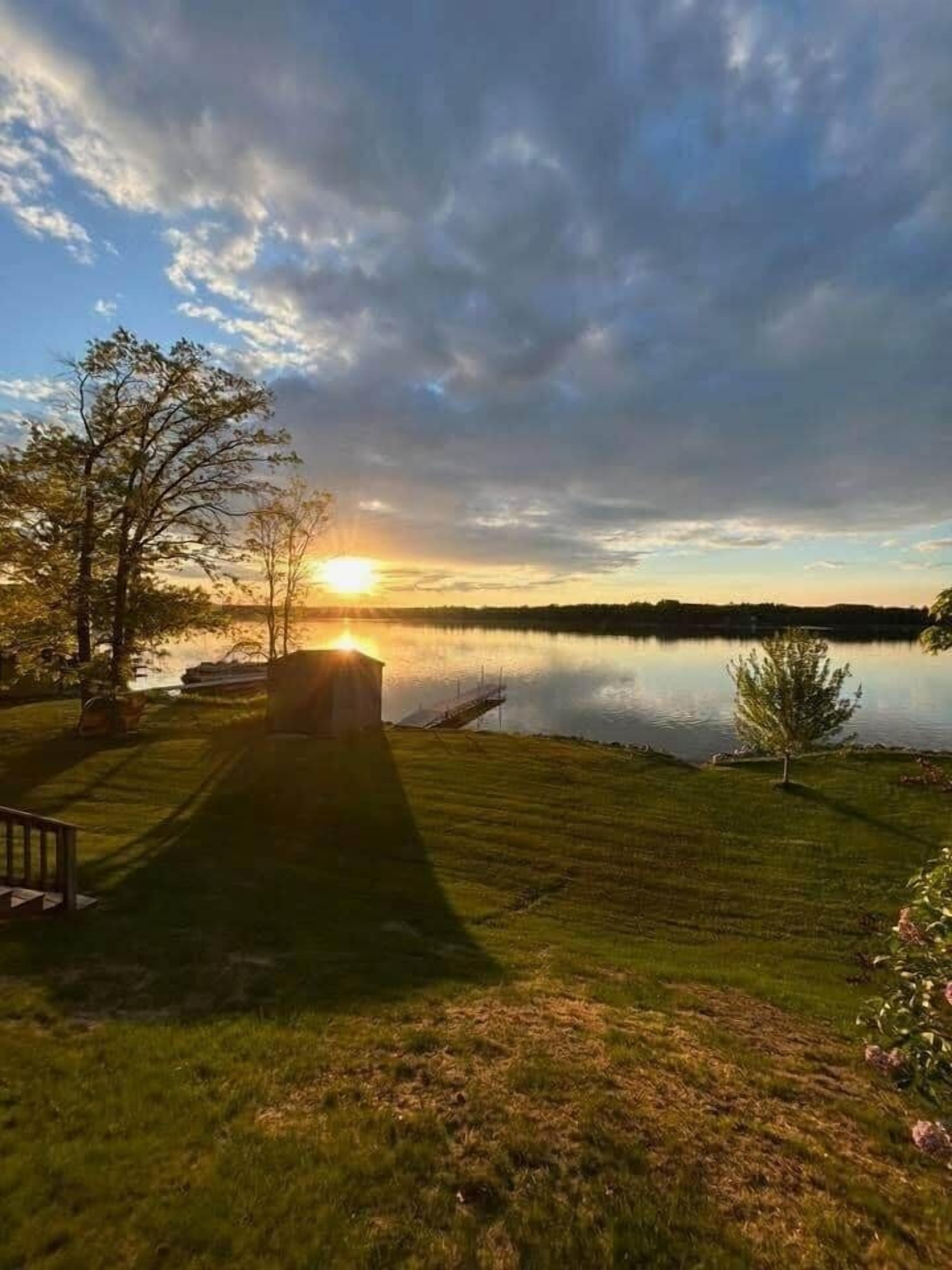 A serene lakeside scene with a wooden deck and a small shed.