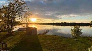 A serene lakeside scene with a wooden deck and a small shed.
