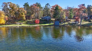 A lakeside property with a dock, a small cabin, and a house with a deck. - The Cozy Cub (Crosslake)