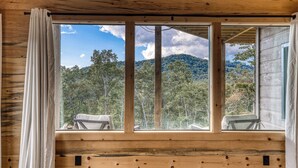 Una baita di legno con un'ampia finestra che si affaccia su una montagna boscosa.