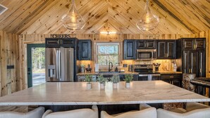 Un'ampia cucina con una grande isola, mobili in legno scuro, elettrodomestici in acciaio inossidabile e vista sull'esterno.