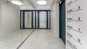 A modern hallway with glass doors, numbered signs, and a floor-to-ceiling mirror.