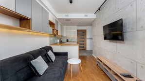 Un salon moderne avec un canapé noir, une petite table blanche et un banc en bois.