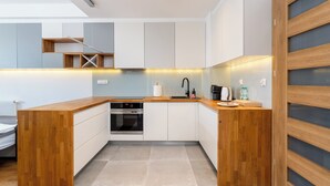 Une cuisine moderne dotée d’un plan de travail en bois, d’un four encastré et de meubles de rangement blancs.