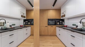 A modern kitchen with white cabinets, wooden accents, and black appliances. - Kluczborska Chic Studio (Kraków)