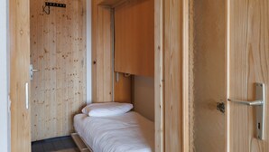 Una habitación de madera con cama, armario y una puerta con pomo.