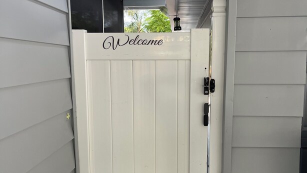 A white gate with a "Welcome" sign, a metal door, and a concrete floor. - Charming 1-bedroom apartment with AC, WiFi in delightful Tampa (Tampa)
