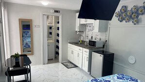 A compact room with a bed, a small desk with a chair, a kitchenette with a microwave, and a bathroom with a shower curtain. - Charming 1-bedroom apartment with AC, WiFi in delightful Tampa (Tampa)
