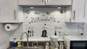 A kitchen with white cabinets, a stainless steel sink, a coffee maker, and jars on the counter. - Charming 1-bedroom apartment with AC, WiFi in delightful Tampa (Tampa)